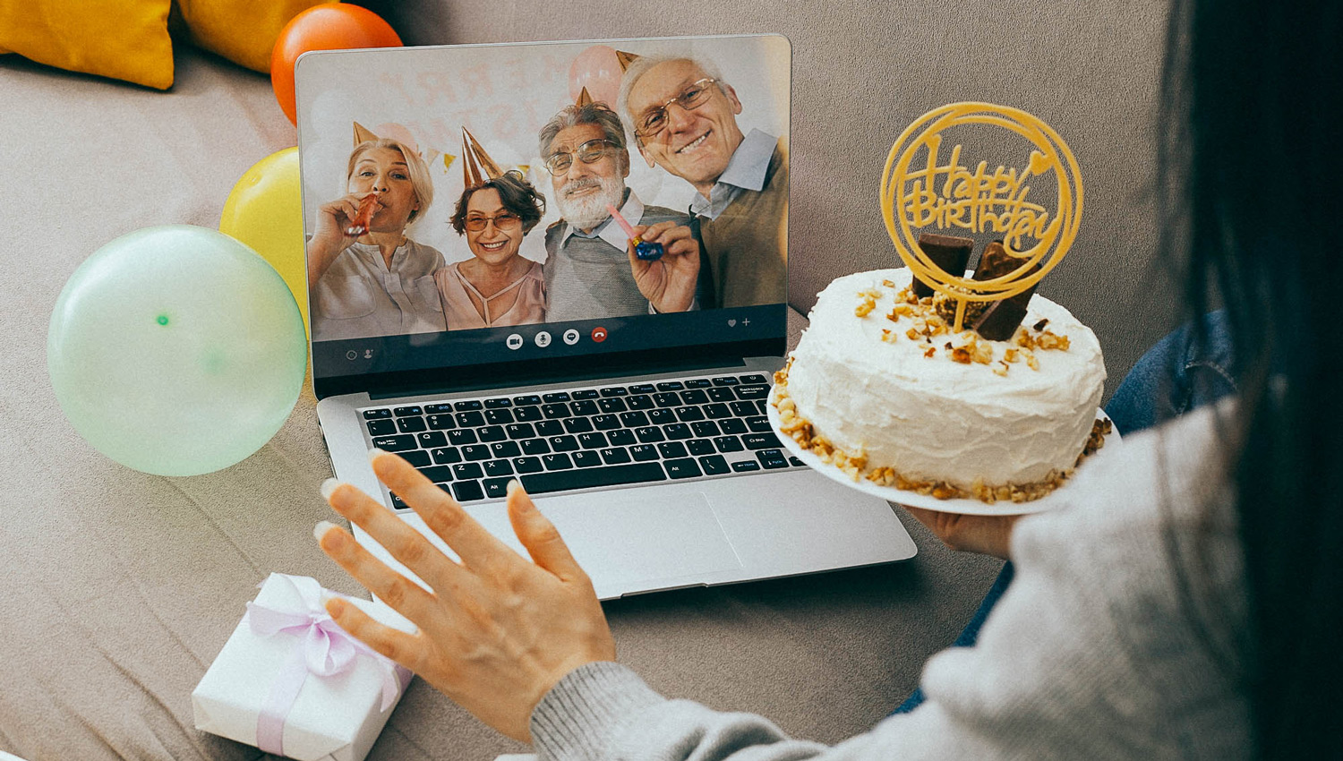 woman holding birthday cake and video calling her family