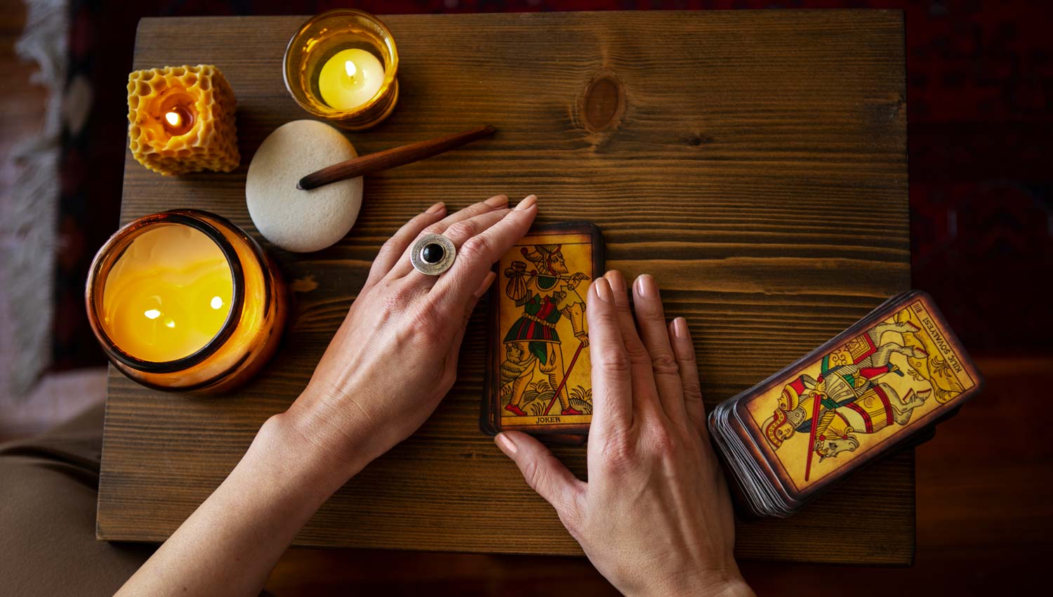 A peaceful close-up of hands gently resting on a tarot deck, with face-down cards, candlelight, and incense nearby, creating a meditative and grounding moment before beginning the tarot reading.