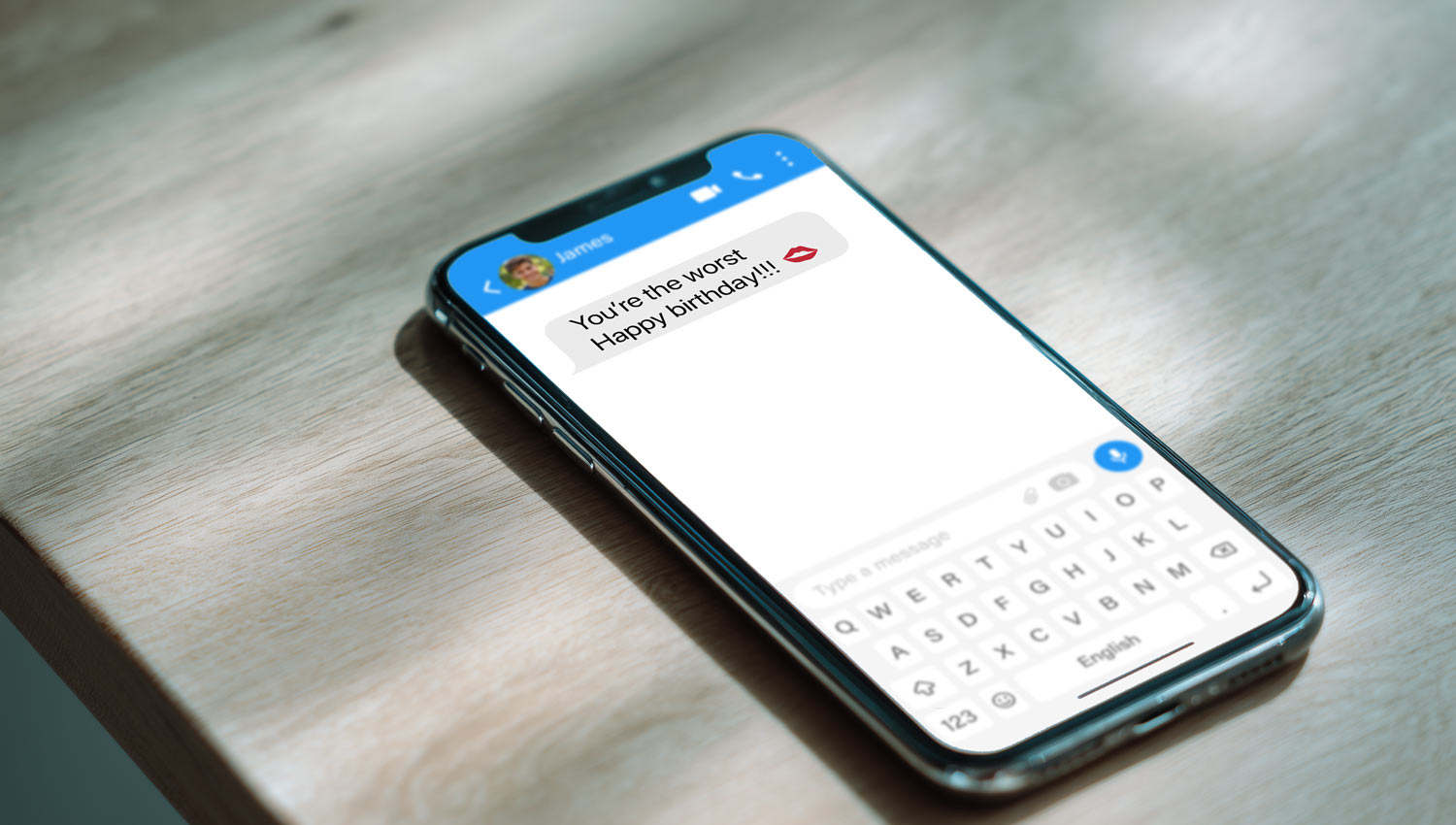 A text message screen with “you’re the worst, happy birthday 💋” and a heart react.