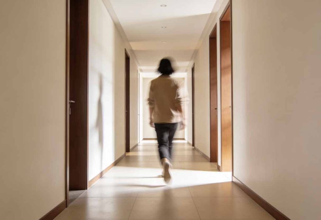A person walking away down a clean, modern hallway or sidewalk, slightly out of focus, captured mid-step