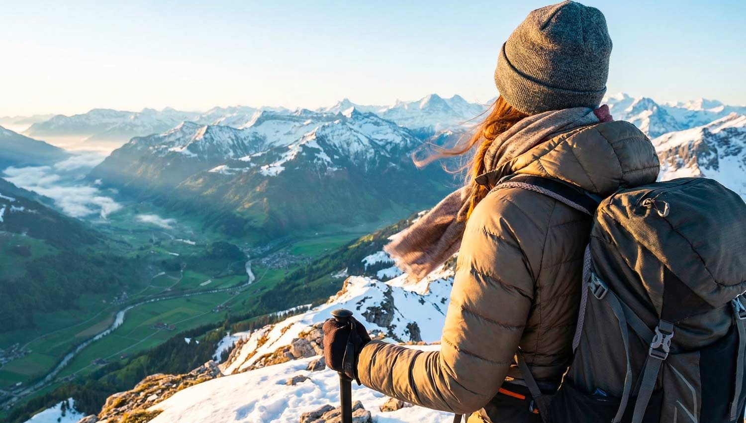 A realistic outdoor adventure scene showing a person standing on a mountain peak at sunrise, looking out over endless landscapes. A sense of excitement and courage is captured as wind gently moves their clothes. The lighting is vibrant and uplifting, symbolizing new journeys and bold decisions.